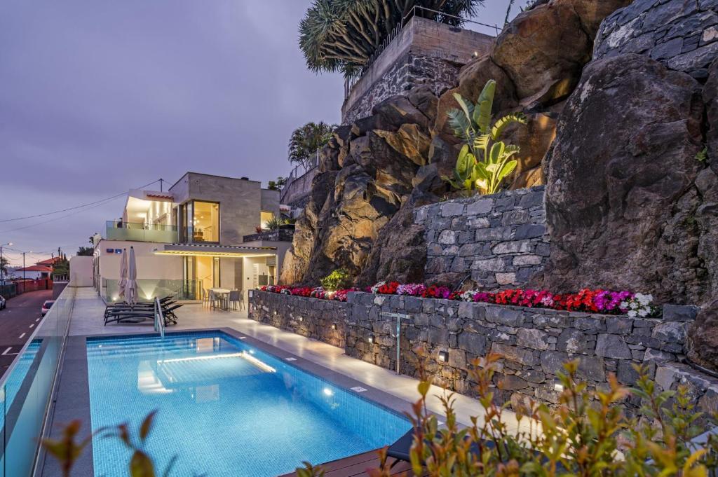 a swimming pool in front of a rock wall at Villa Grandview by Villa Plus in Funchal