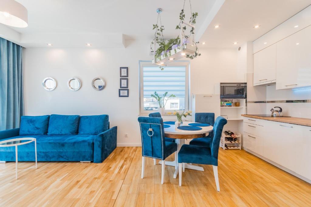 sala de estar con sofá azul, mesa y sillas en Apartament Rowerowo przez Mierzeję, rowery gratis, en Sztutowo