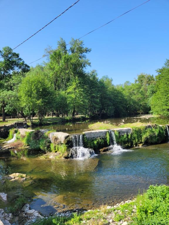 einem Wasserfall in einem Fluss mit Bäumen im Hintergrund in der Unterkunft Appartement ardeche vallée de l'ouvèze SANS extérieur mais à proximité de parcs in Flaviac