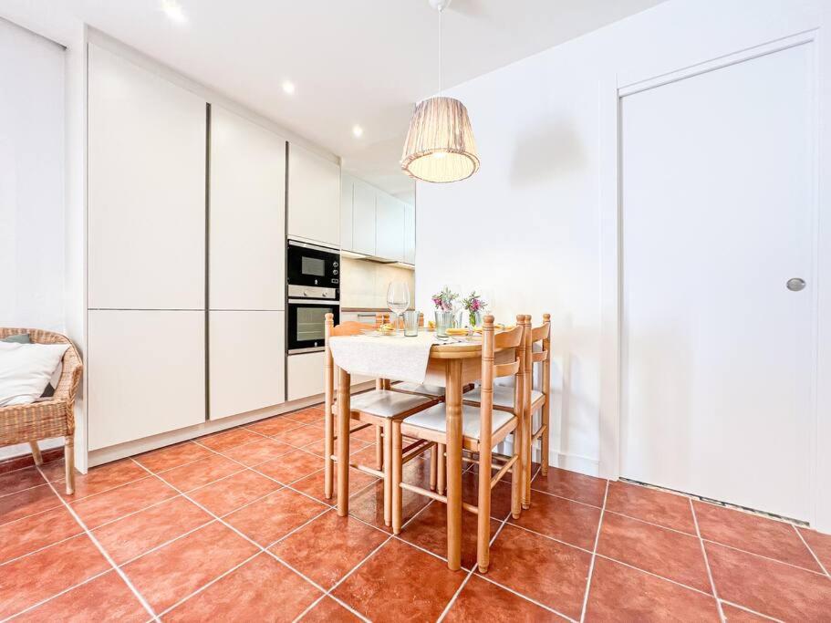a kitchen with white cabinets and a table and chairs at Apartament 'Es Botànic' in Blanes