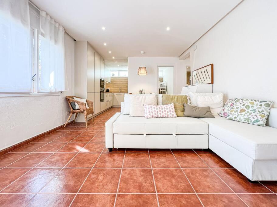 a living room with a white couch on a tile floor at Apartament 'Es Botànic' in Blanes