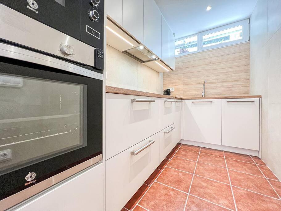 a kitchen with white cabinets and a stove top oven at Apartament 'Es Botànic' in Blanes