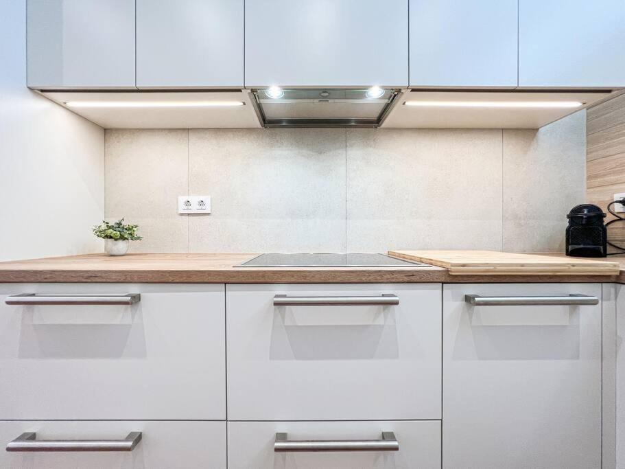 a kitchen with white cabinets and a wooden counter top at Apartament 'Es Botànic' in Blanes