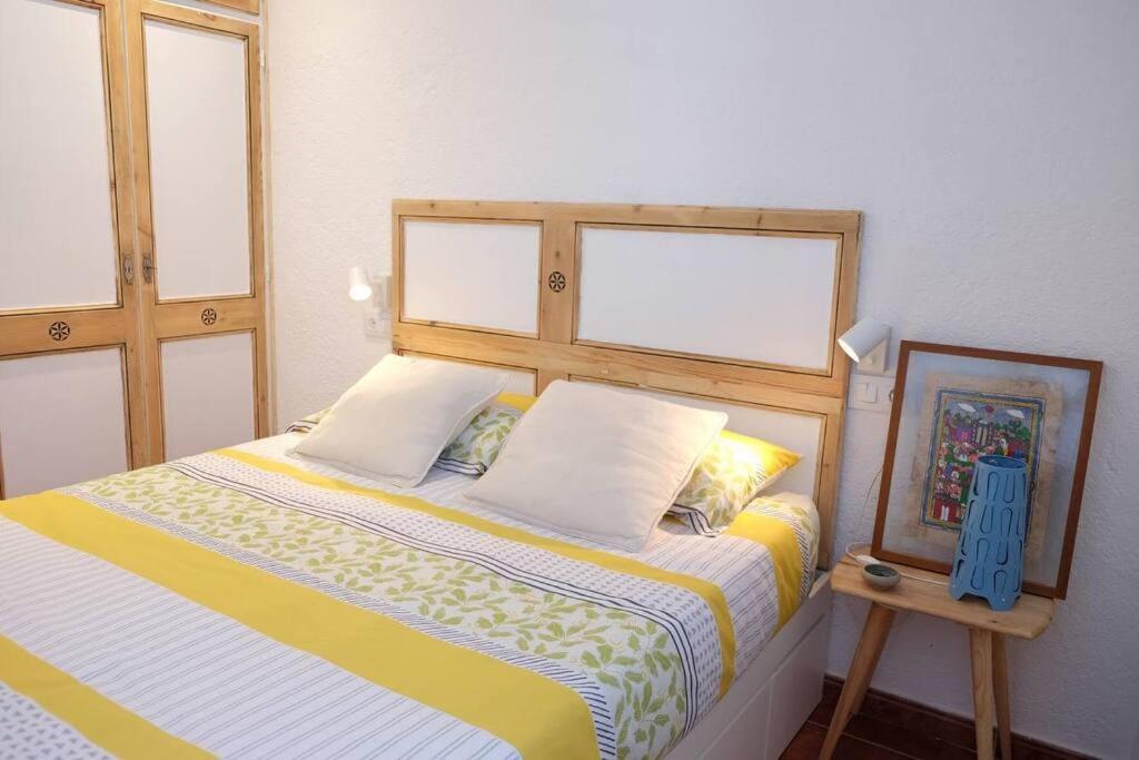 a bedroom with a bed with a yellow and white comforter at Apartament 'Es Botànic' in Blanes
