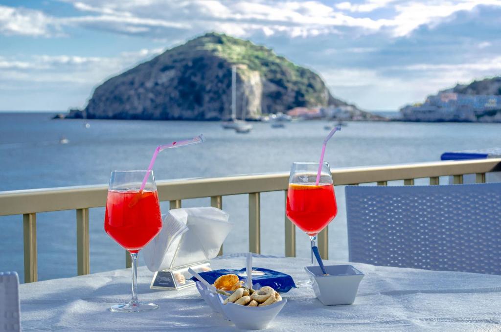 two wine glasses sitting on a table with a view of the ocean at Hotel Regina del Mare in Ischia