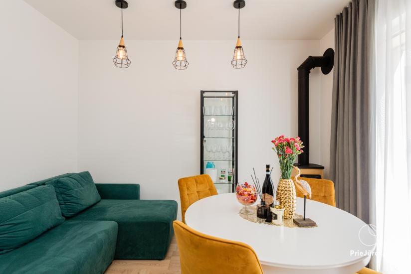 a living room with a table and a green couch at Čiki Puki Pajūrys in Palanga