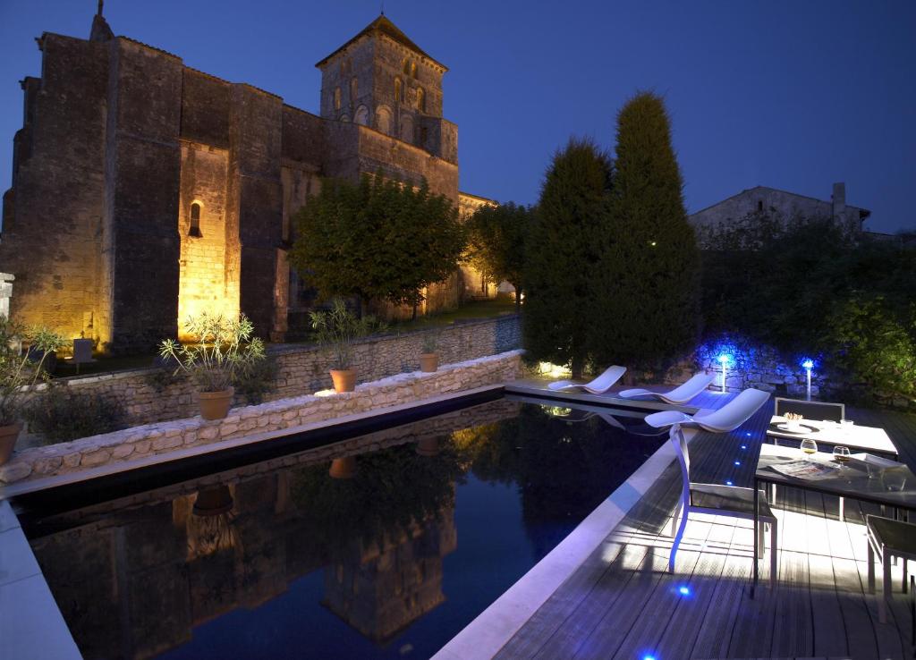 - une piscine en face d'un château la nuit dans l'établissement Design Hôtel des Francs Garçons, à Saint-Sauvant