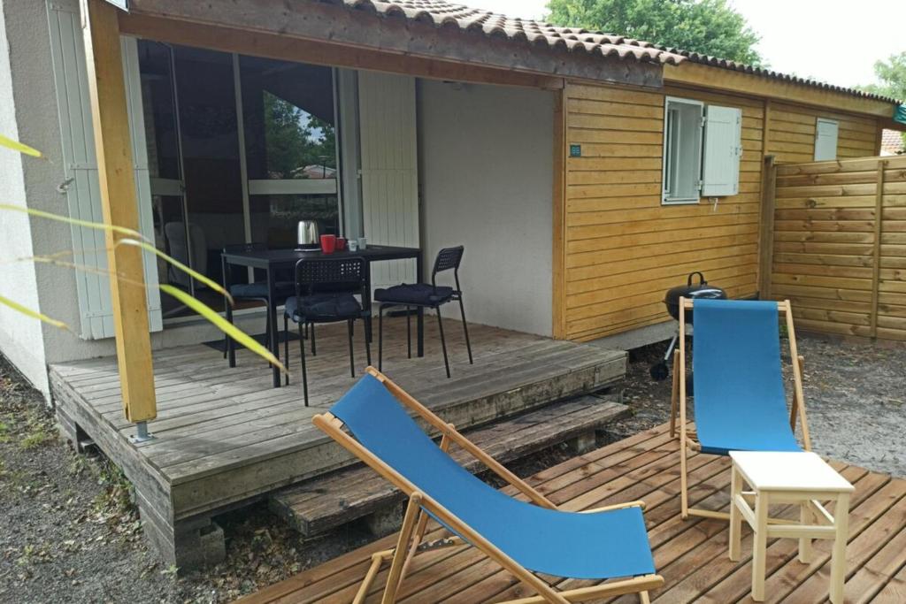 a wooden deck with chairs and a table on it at Cozy chalet des Moussaillons N99 - proche lac in Hourtin