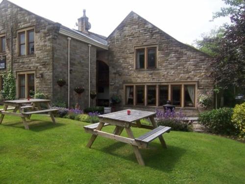 two picnic tables in front of a stone house at The Waltzing Weasel B&B in Birch Vale