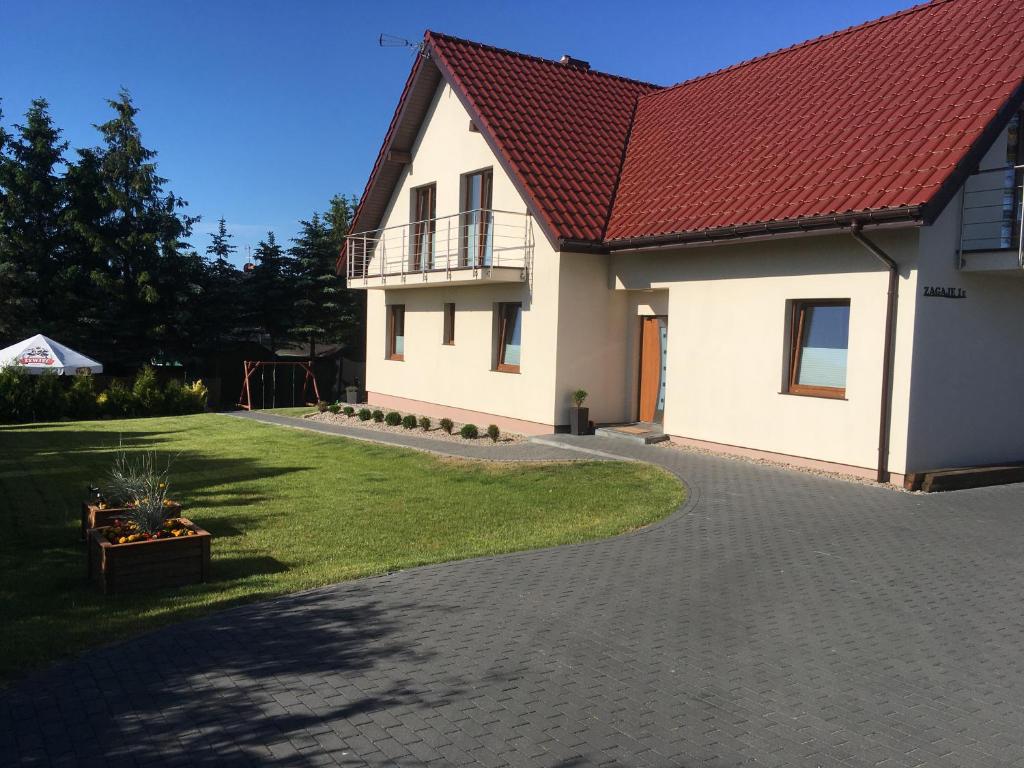 a house with a red roof and a driveway at Sielska Chatka Zagaje in Sarbinowo