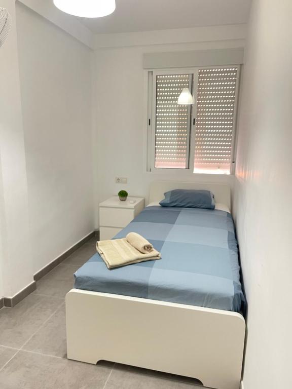 a white bedroom with a bed and two windows at UIM Mediterraneo Alicante Wifi in Puerto de Sagunto