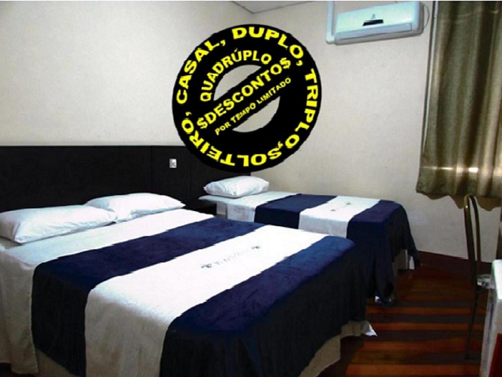 2 camas en una habitación con un cartel en la pared en Hotel Minho -Próximo , 25 Março, Brás e Bom Retiro Esquina com rua dos Eletrônicos, en São Paulo