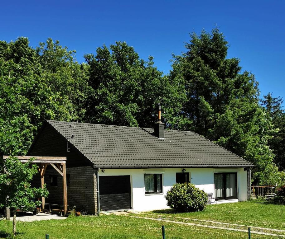 een wit en zwart huis met bomen op de achtergrond bij Bungalow Rochehaut au calme in Rochehaut