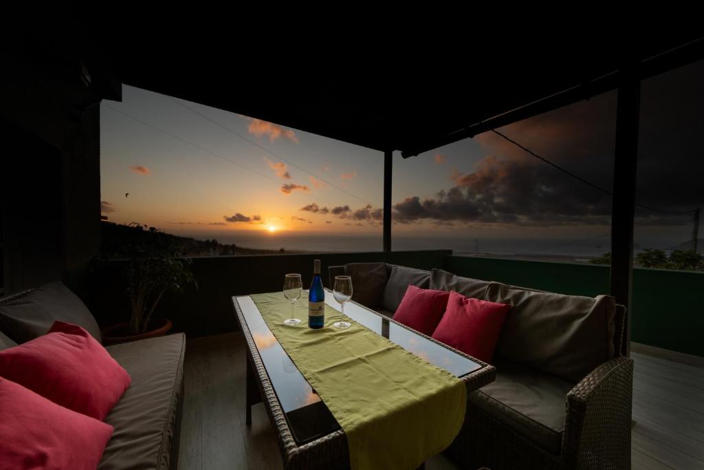 einen Tisch und Stühle auf einem Balkon mit Blick auf den Sonnenuntergang in der Unterkunft Vivienda Vacacional Efriland in Frontera
