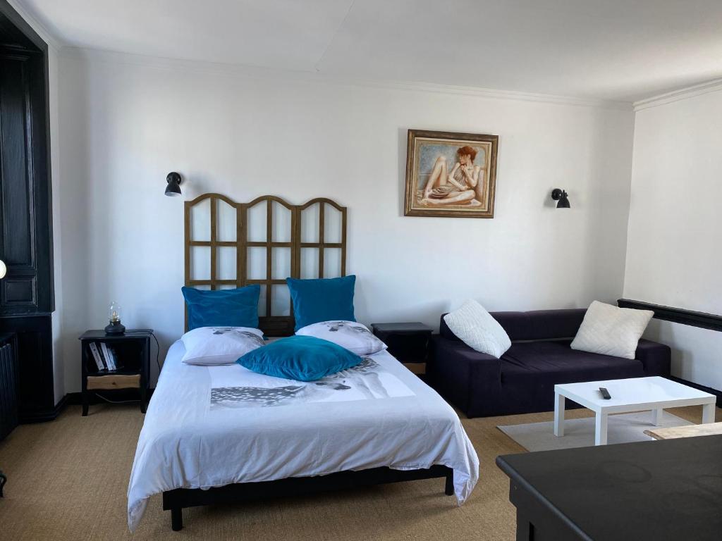 格朗維爾的住宿－CHAMBRE SPACIEUSE DANS MAISON RENOVEE，一间卧室配有一张带蓝色枕头的床和一张沙发。