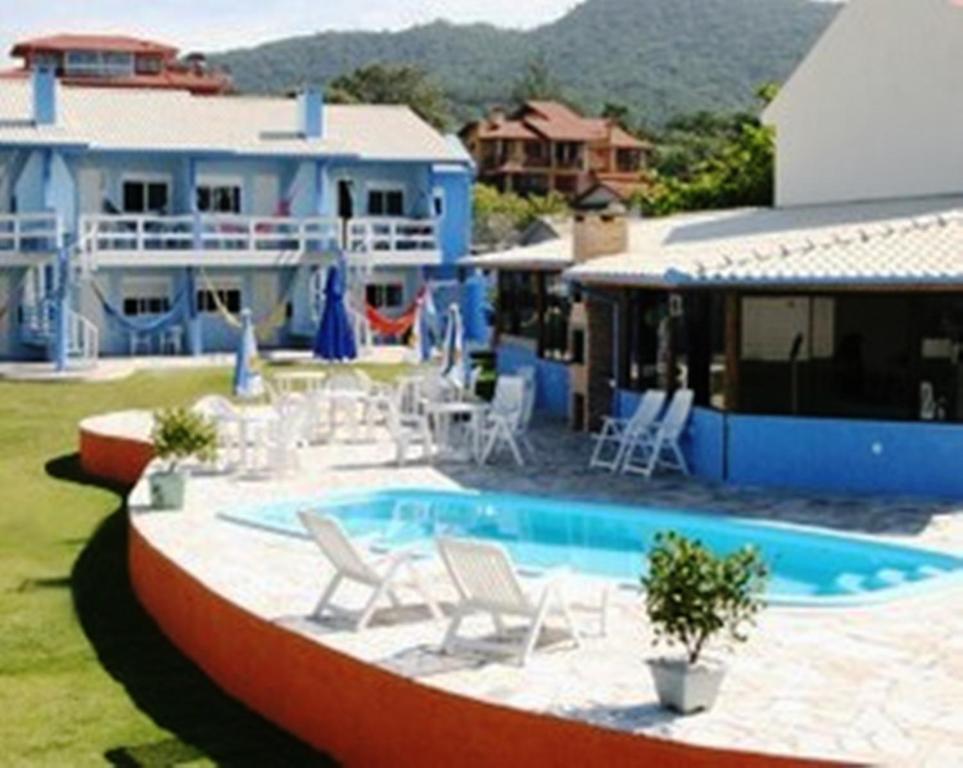 a swimming pool with chairs and a house at Pousada Praia da Villa in Imbituba