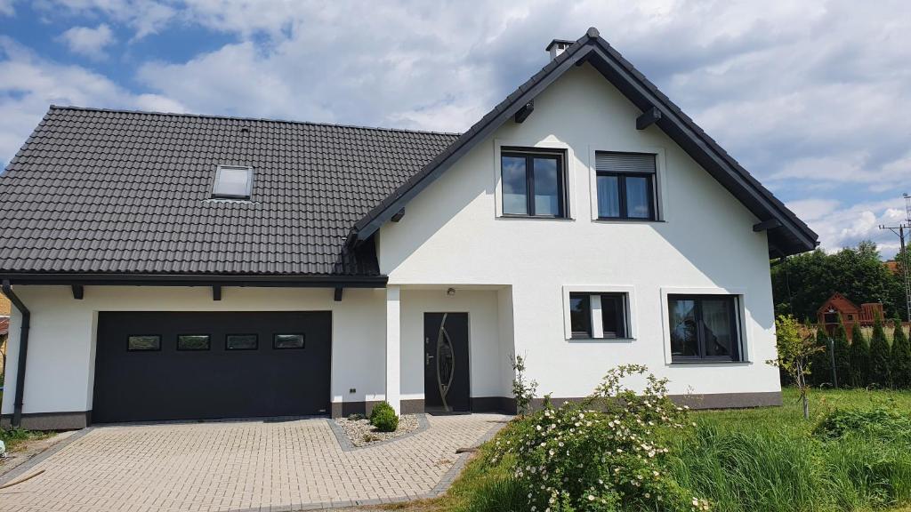 une maison blanche avec un toit noir et un garage dans l'établissement Dom Zakątek, Kudowa Zdrój, à Kudowa-Zdrój