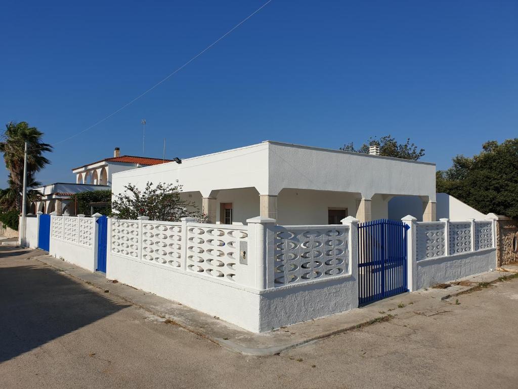 una casa blanca con una valla azul en Villetta Azzurra, en Torre Lapillo