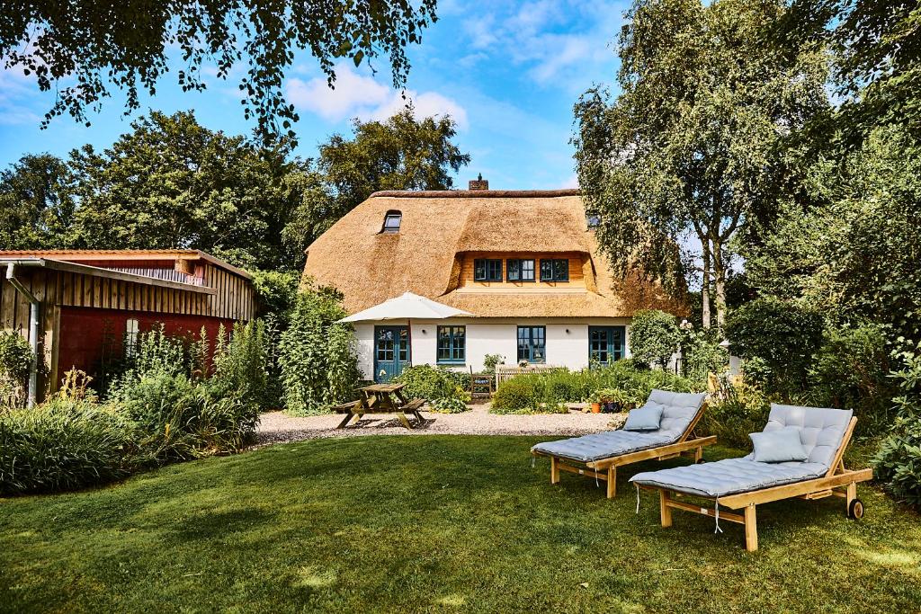 a house with a thatched roof and two chairs in the yard at MeinNest31 in Sankt Peter-Ording