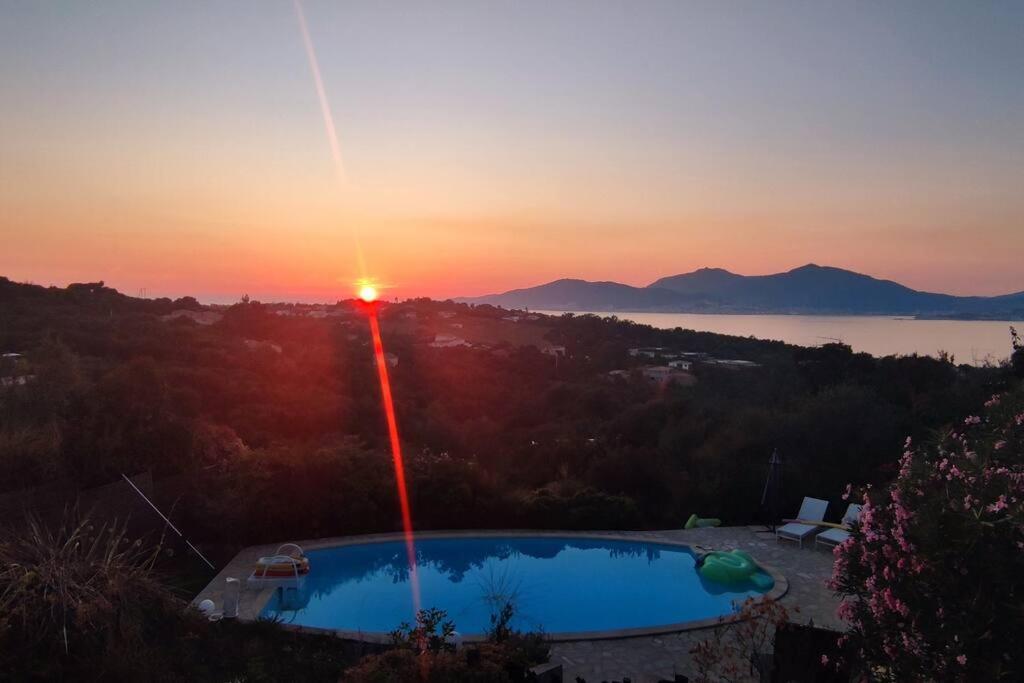 un coucher de soleil au-dessus d'une piscine avec le coucher de soleil en arrière-plan dans l'établissement F4 à Porticcio avec piscine et vue sur mer, à Porticcio