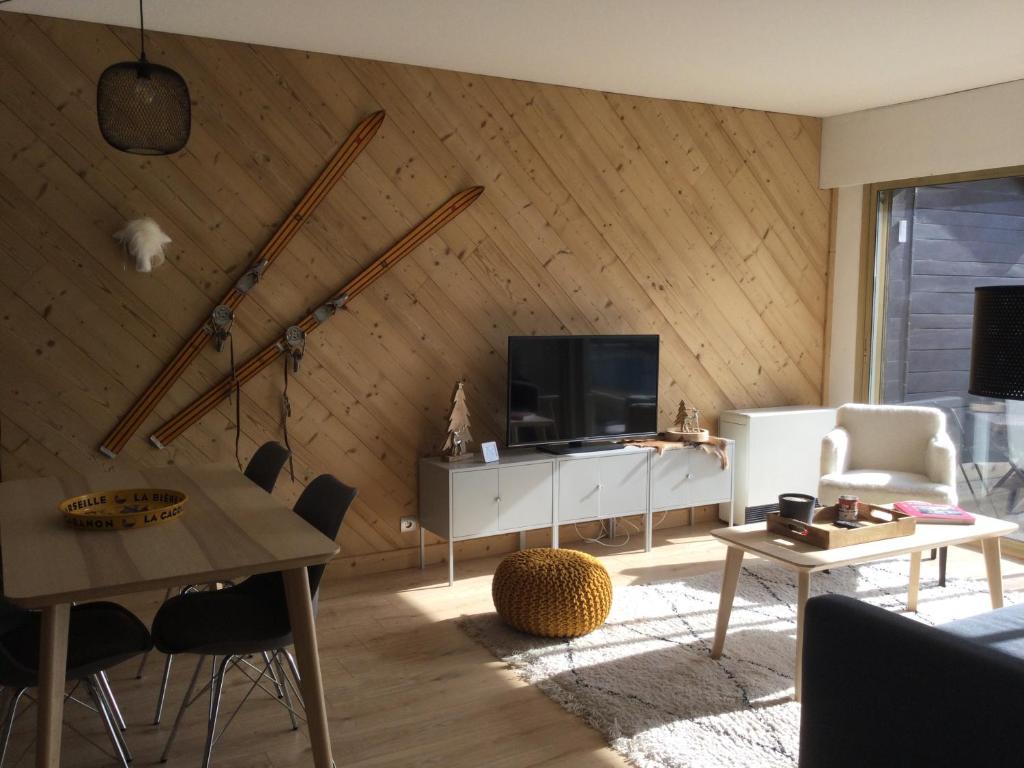 a living room with a wooden wall with a television at Appartement centre Barcelonnette in Barcelonnette