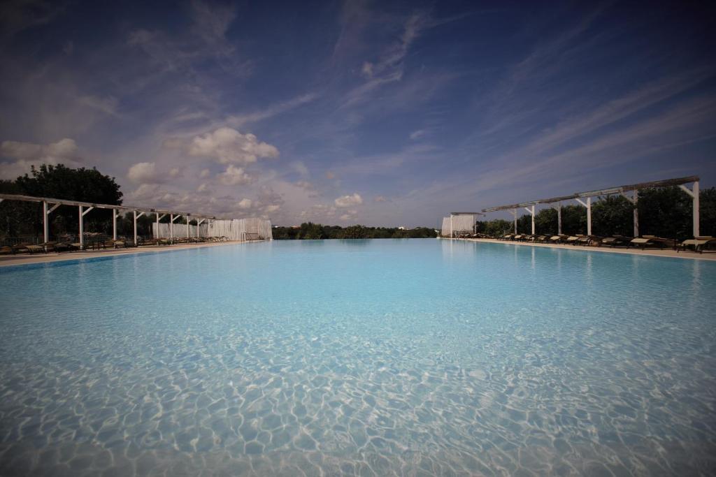 duży basen z niebieską wodą z niebieskim niebem w obiekcie Casale del Murgese Country Resort w mieście Savelletri di Fasano