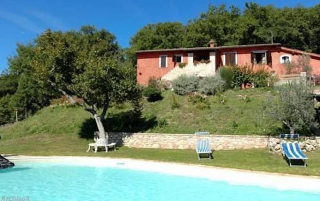 a house with two lawn chairs and a swimming pool at Casale Rosso in Castel San Felice
