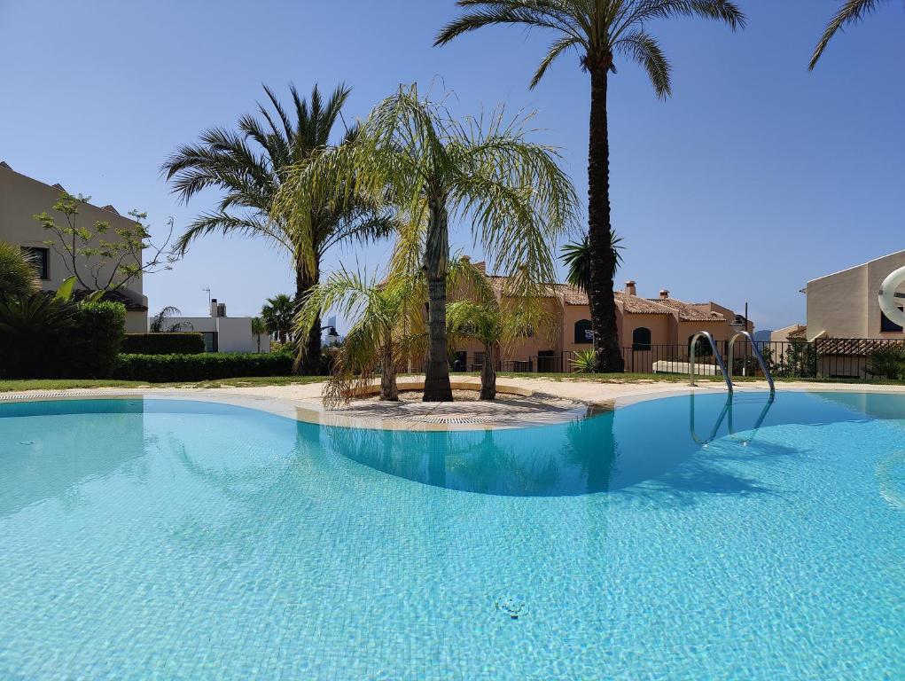 een groot zwembad met palmbomen voor een huis bij MIRADOR vacation home in Cala de Finestrat