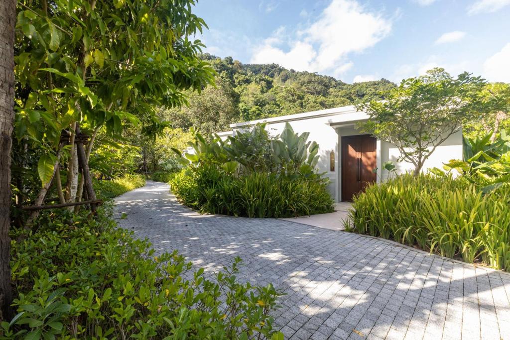 a path leading to a white house with trees at InterContinental Phuket Resort by IHG in Kamala Beach