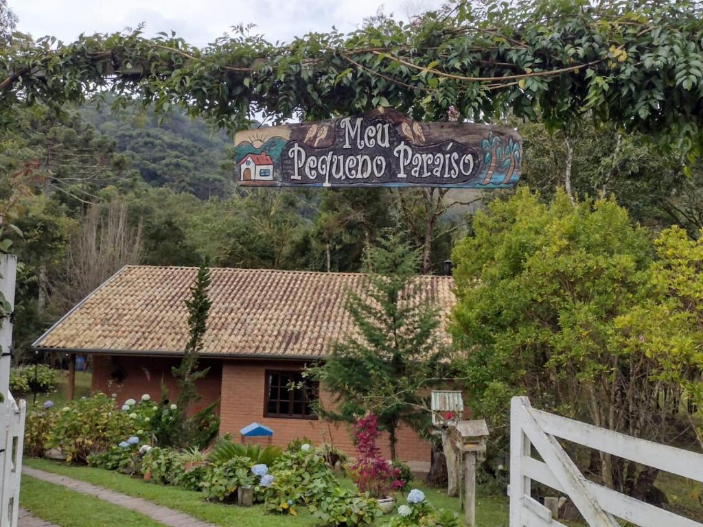 a sign in front of a house with a fence at Casa de Campo Meu Pequeno Paraíso in Gonçalves