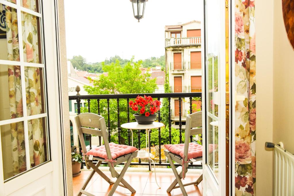 een balkon met 2 stoelen en een tafel met een vaas met bloemen bij Miranda VUT-PO-004637 in Caldas de Reis
