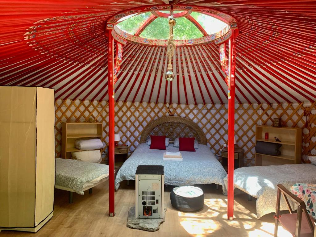a red tent with two beds and a window at La Yurta de Gaia in San Lorenzo de El Escorial