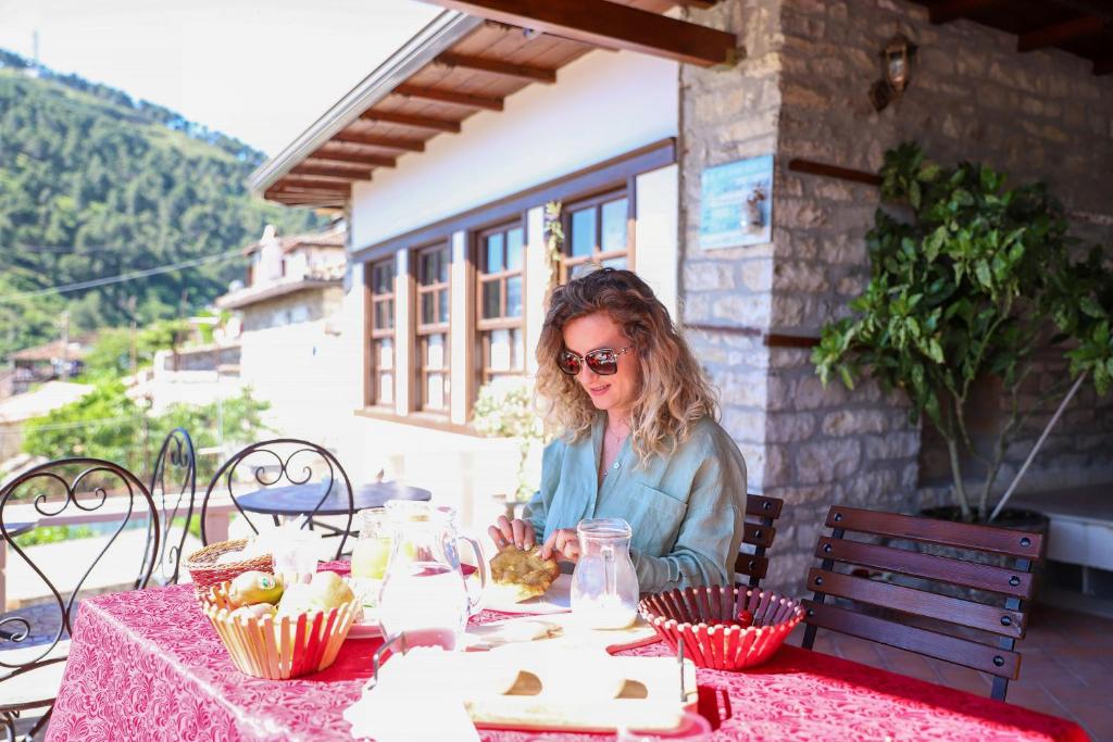 a woman sitting at a table with a pink table cloth at Hotel Borklad in Berat