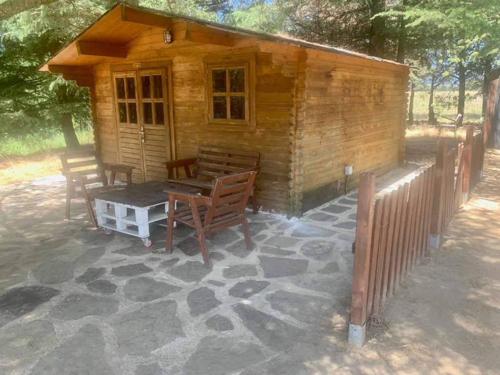 a log cabin with a table and chairs outside at La Cabaña de Gaia in San Lorenzo de El Escorial