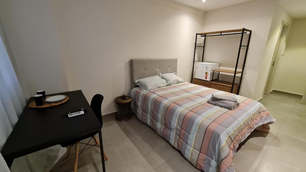 a bedroom with a bed with a table and a mirror at Flat Hotel América Campos Pelinca 301 in Campos dos Goytacazes