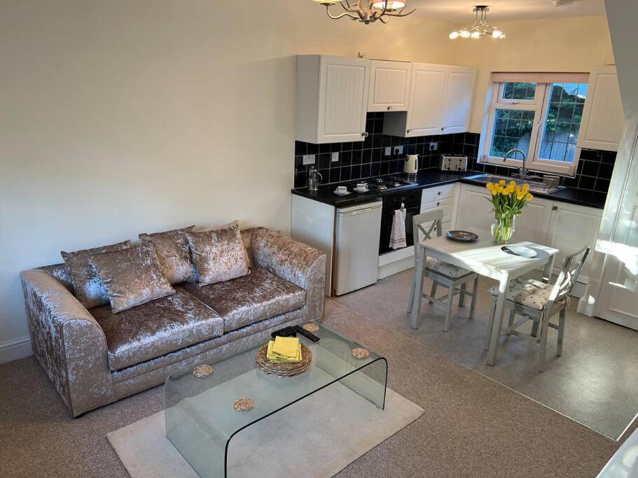 a living room with a couch and a table at Self contained, spacious annex with private drive. in Kent