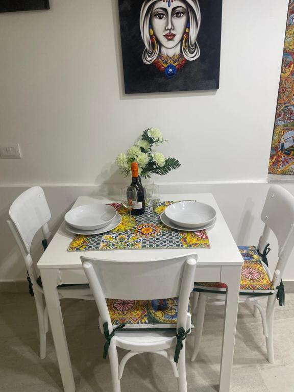 uma mesa branca com cadeiras e uma garrafa de vinho em Mega House 2 em Catânia