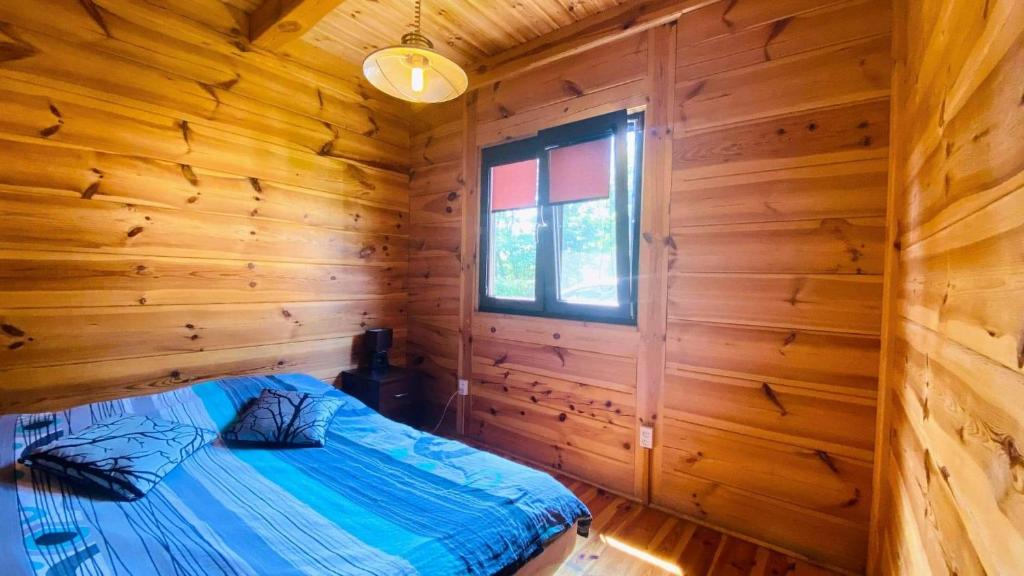 um quarto com uma cama num chalé de madeira em Domki i pokoje nad rzeką Wieprz em Zwierzyniec