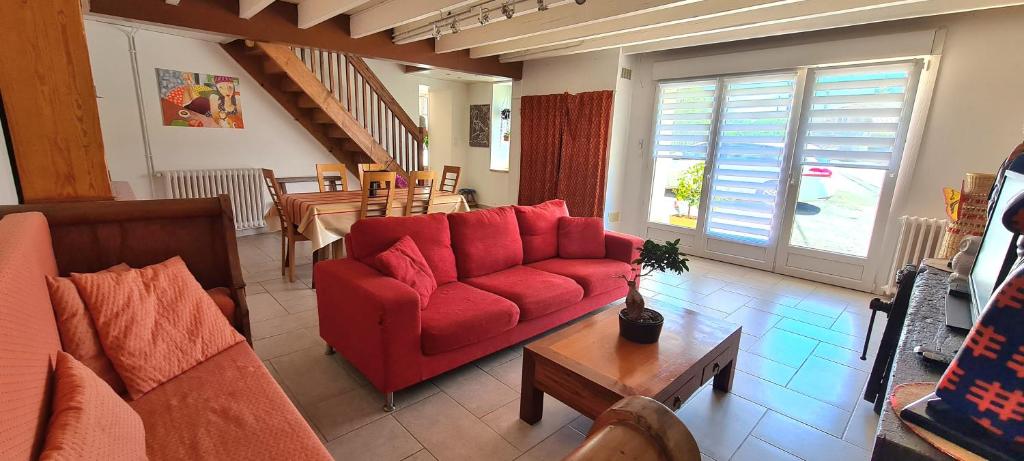 uma sala de estar com um sofá vermelho e uma mesa em La Gelotière propose 2 logements indépendants à 10 min du Puy du Fou em Sevremont