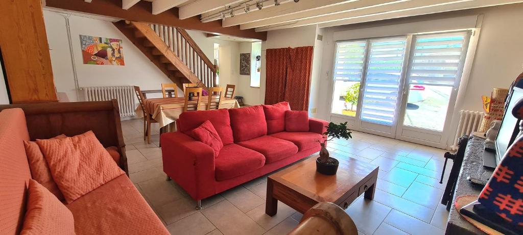 a living room with a red couch and a table at La Gelotière maison de compagne à 10 min du Puy du Fou in Sevremont