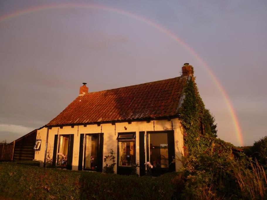 un arco iris sobre una casa con en Dijkhuisje Zeeland, en Waterlandkerkje