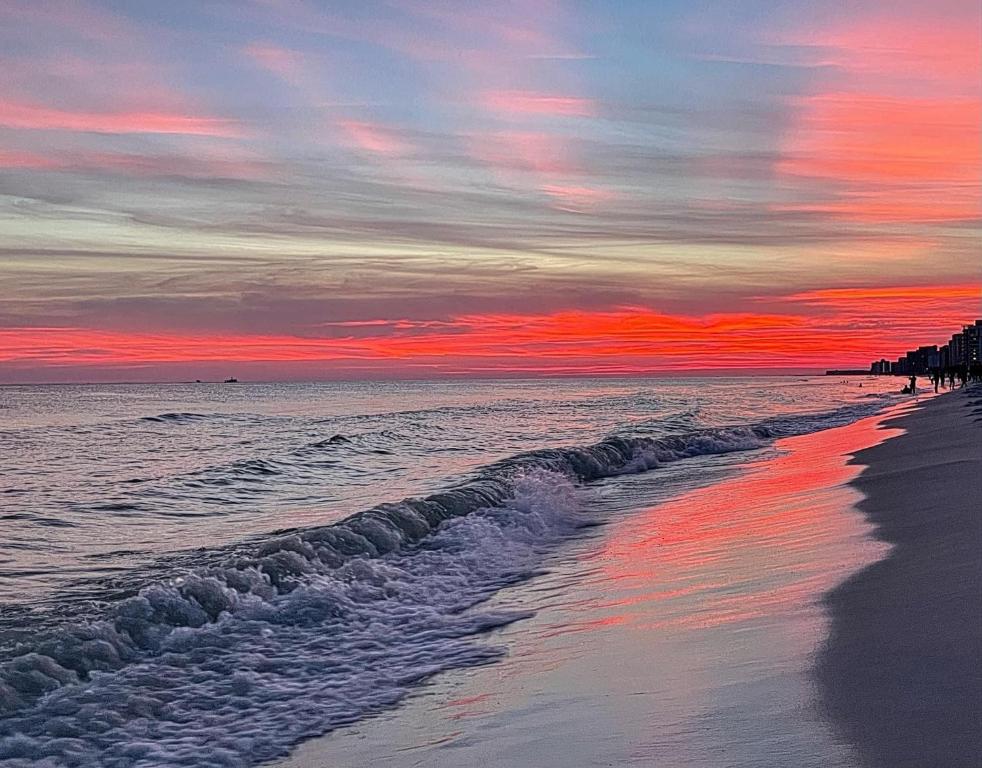 una puesta de sol sobre una playa con el océano en Spectacular Sunsets 5 star Resort Condo Across from Beach Sleep 6 Private Shuttle en Destin