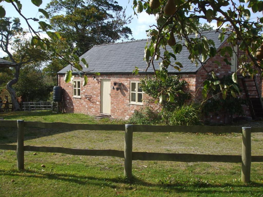 uma casa de tijolos com uma cerca em frente em Little Pentre Barn with pool June - August em Wrexham