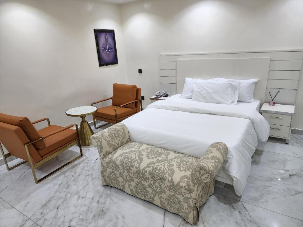 een slaapkamer met een groot bed en een stoel bij LUXOL HOMES&SUITES in Ikeja