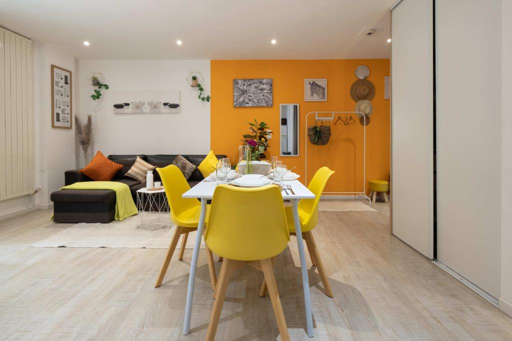 a dining room and living room with a table and yellow chairs at LES FRANKLINS APPARTEMENTS - Hyper CENTRE Mulhouse in Mulhouse