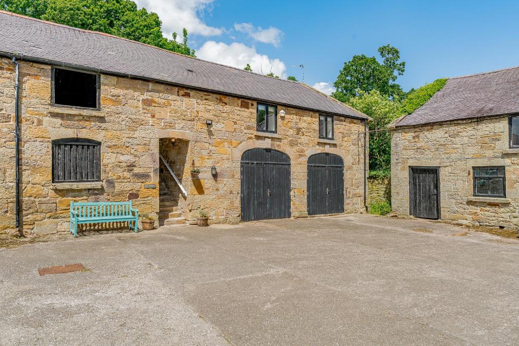 a stone building with two garage doors and a bench at The Hayloft in Mold