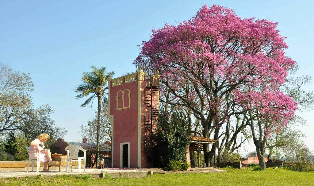 a woman standing next to a tree with pink flowers at Estancia La Titina, Posada y Reserva Natural in Concepción del Uruguay