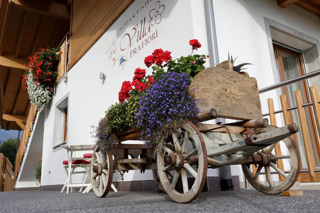 un carrello di legno pieno di fiori di fronte a un edificio di Villa Prafiorì a Cavalese