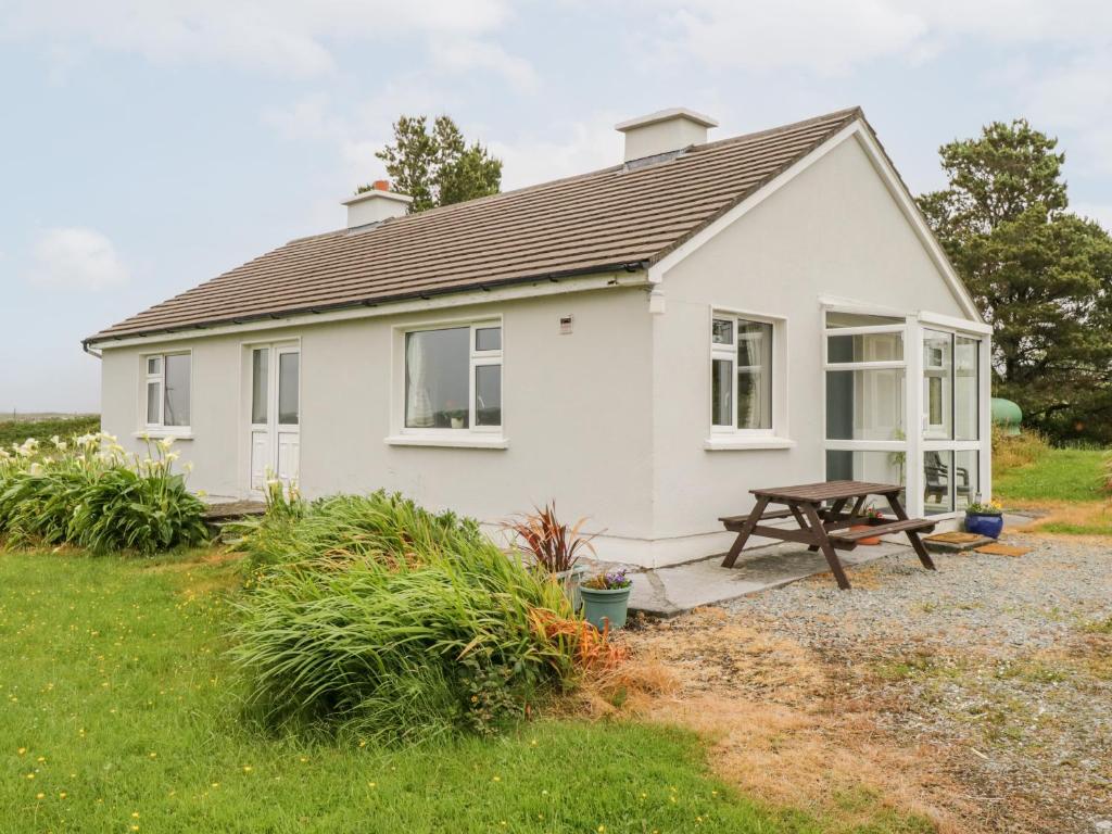 a white house with a picnic table in front of it at Roundstone Bay View in Roundstone