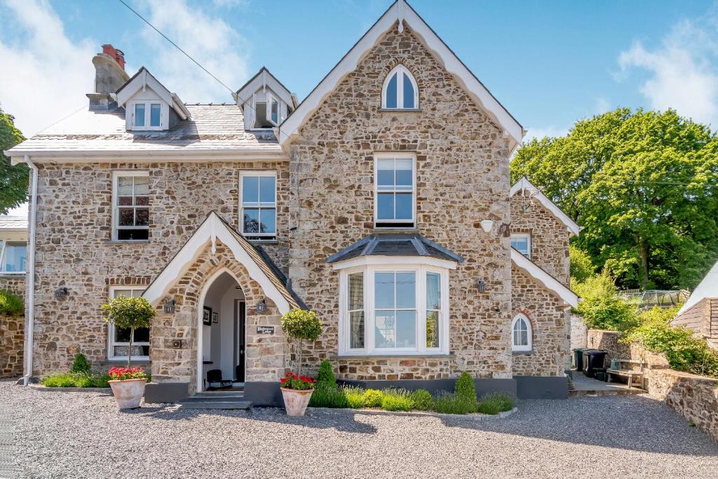 a large stone house with a driveway at Rhodewood Lodge in Saundersfoot